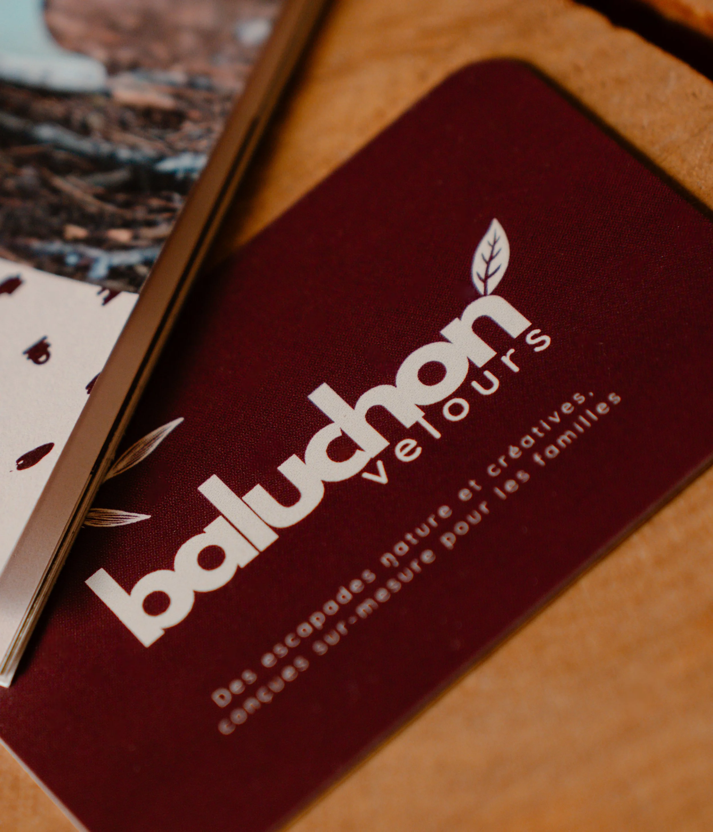 carte de visite baluchon velours sur un support en bois  naturel à côté d'un carnet d'aventure