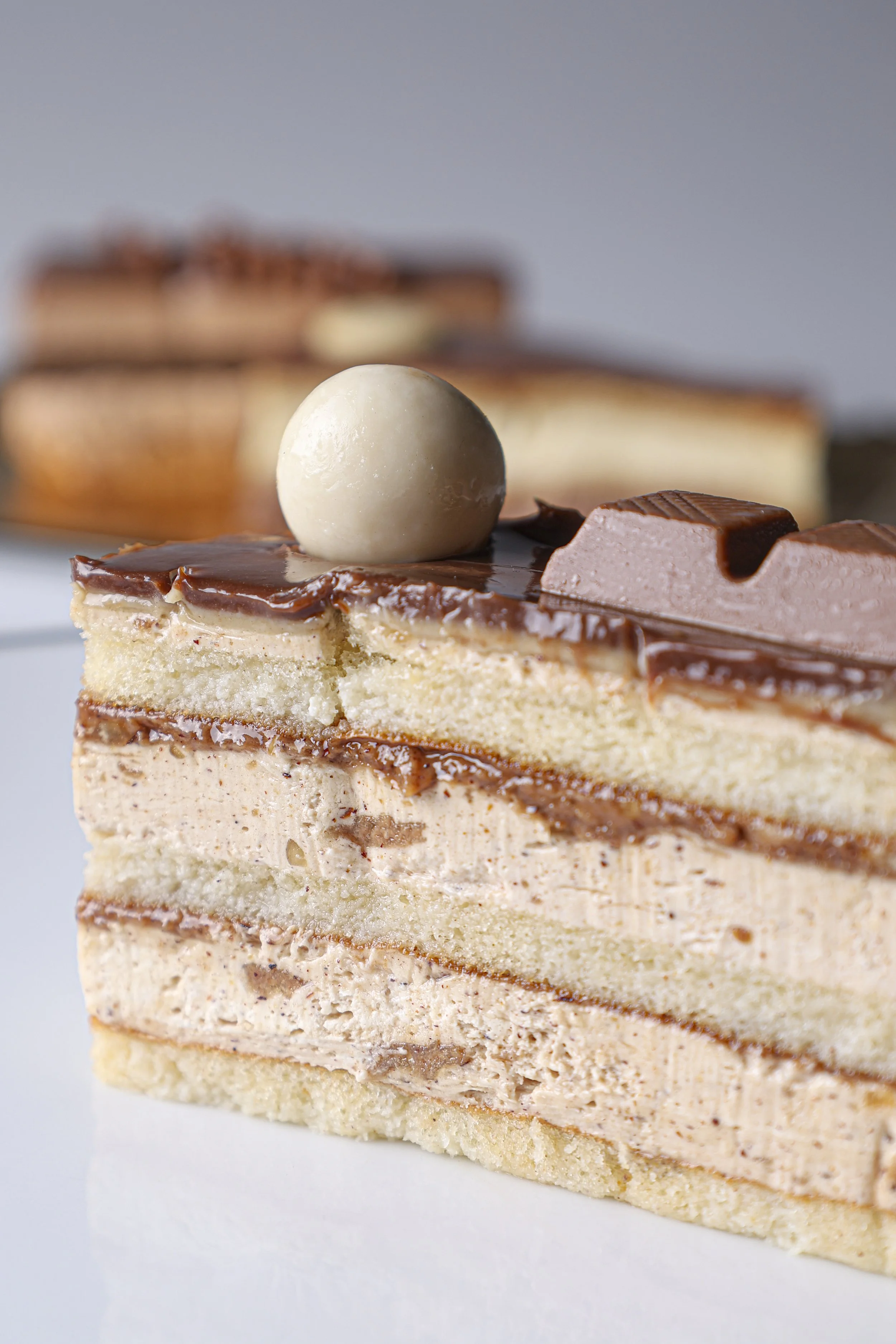 Tarta de capas con chocolate y crema, decorada con una bola de chocolate y trozos de chocolate en la parte superior.