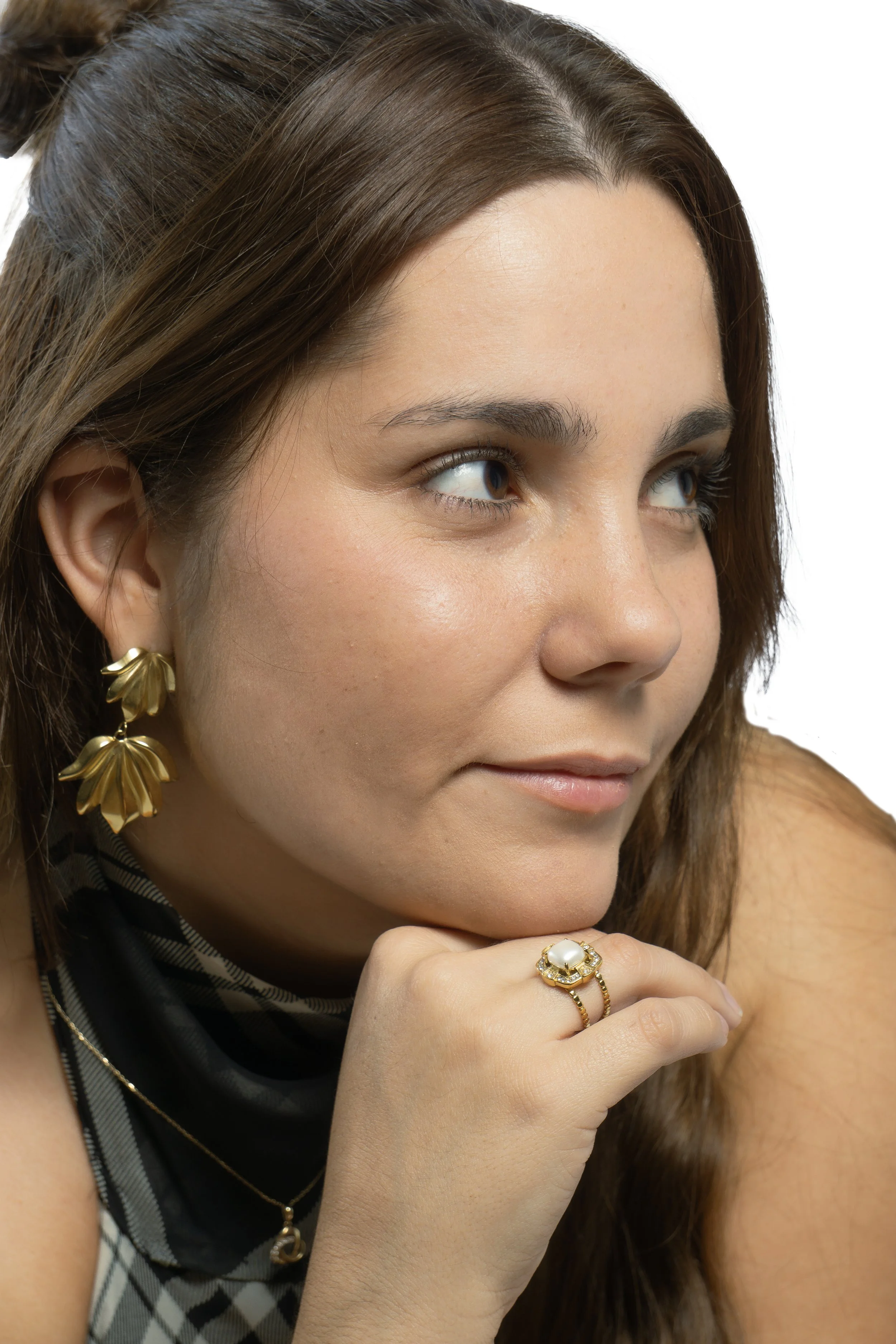 Retrato de una mujer con pendientes dorados y reloj, con pelo castaño y piel clara, mirando hacia la derecha
