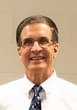 Tim Yoder headshot wearing a white shirt and blue patterned tie.