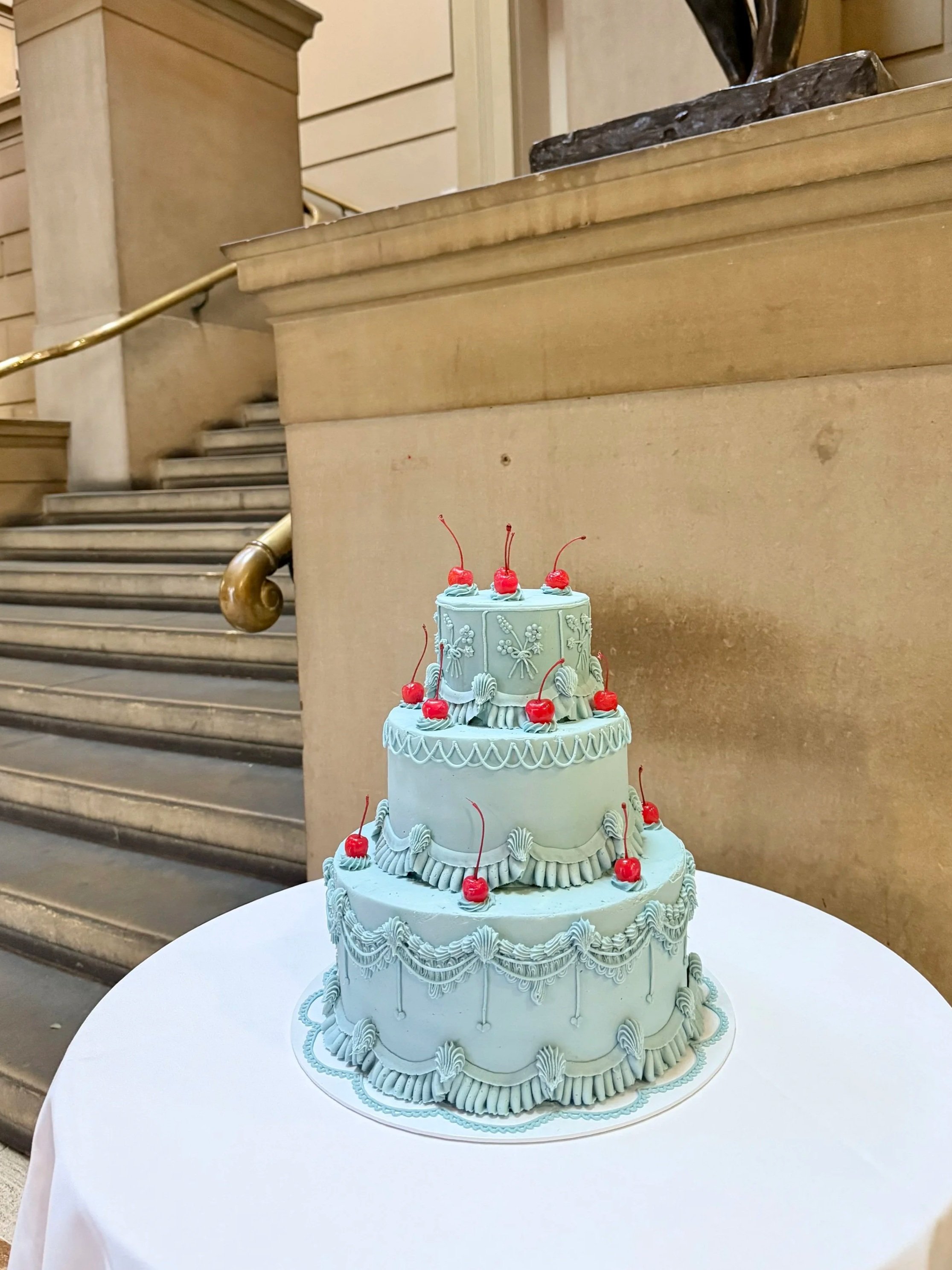 A three-tiered blue wedding cake decorated red cherries 