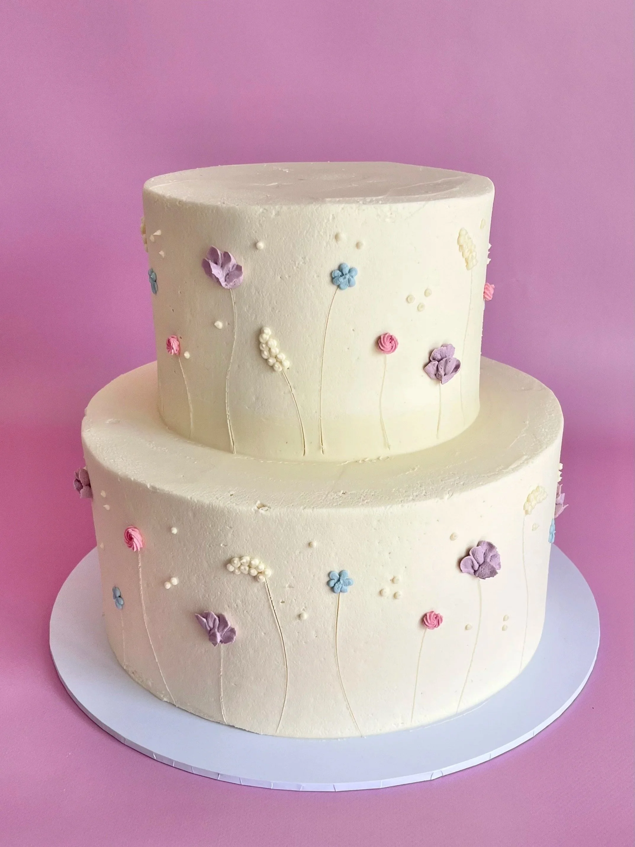 Two-tiered wedding cake decorated with pastel-coloured flowers