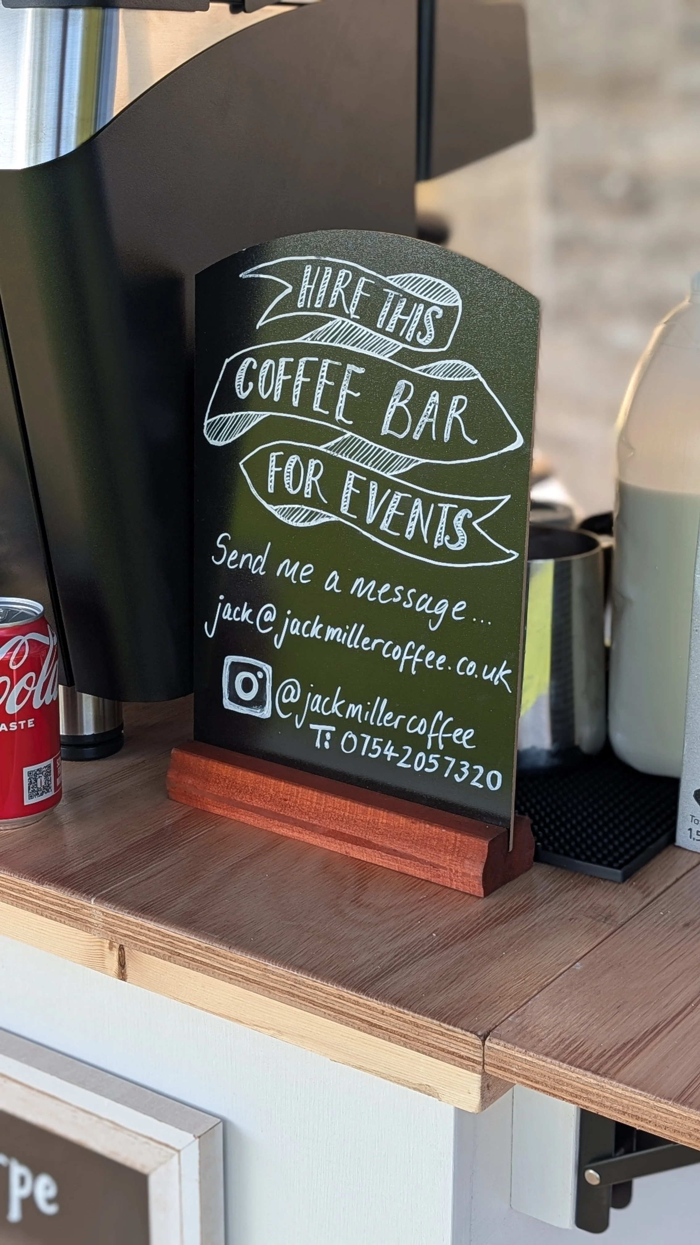Sign advertising hire for a coffee bar at events, with contact information including email, phone number, and social media handles.