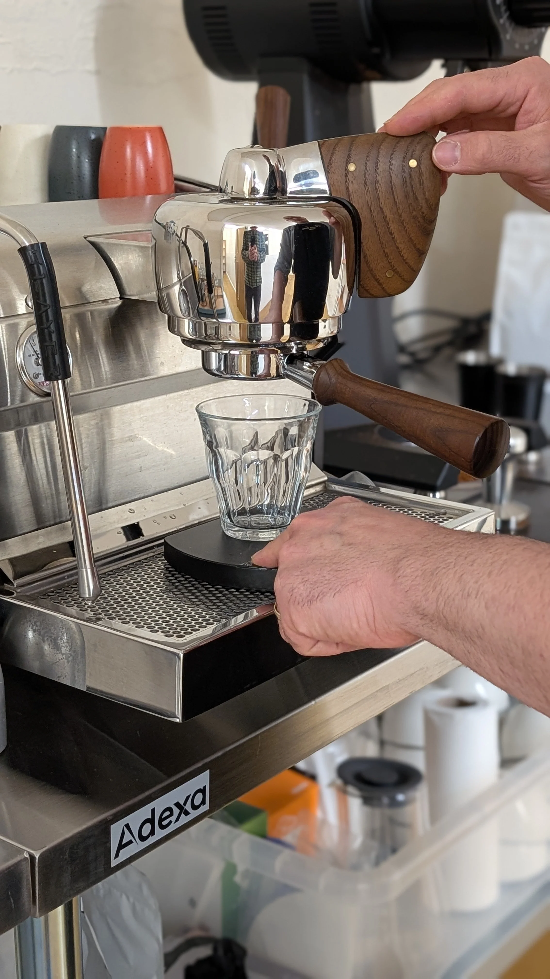 Coffee being brewed with a manual espresso machine and a glass cup underneath.