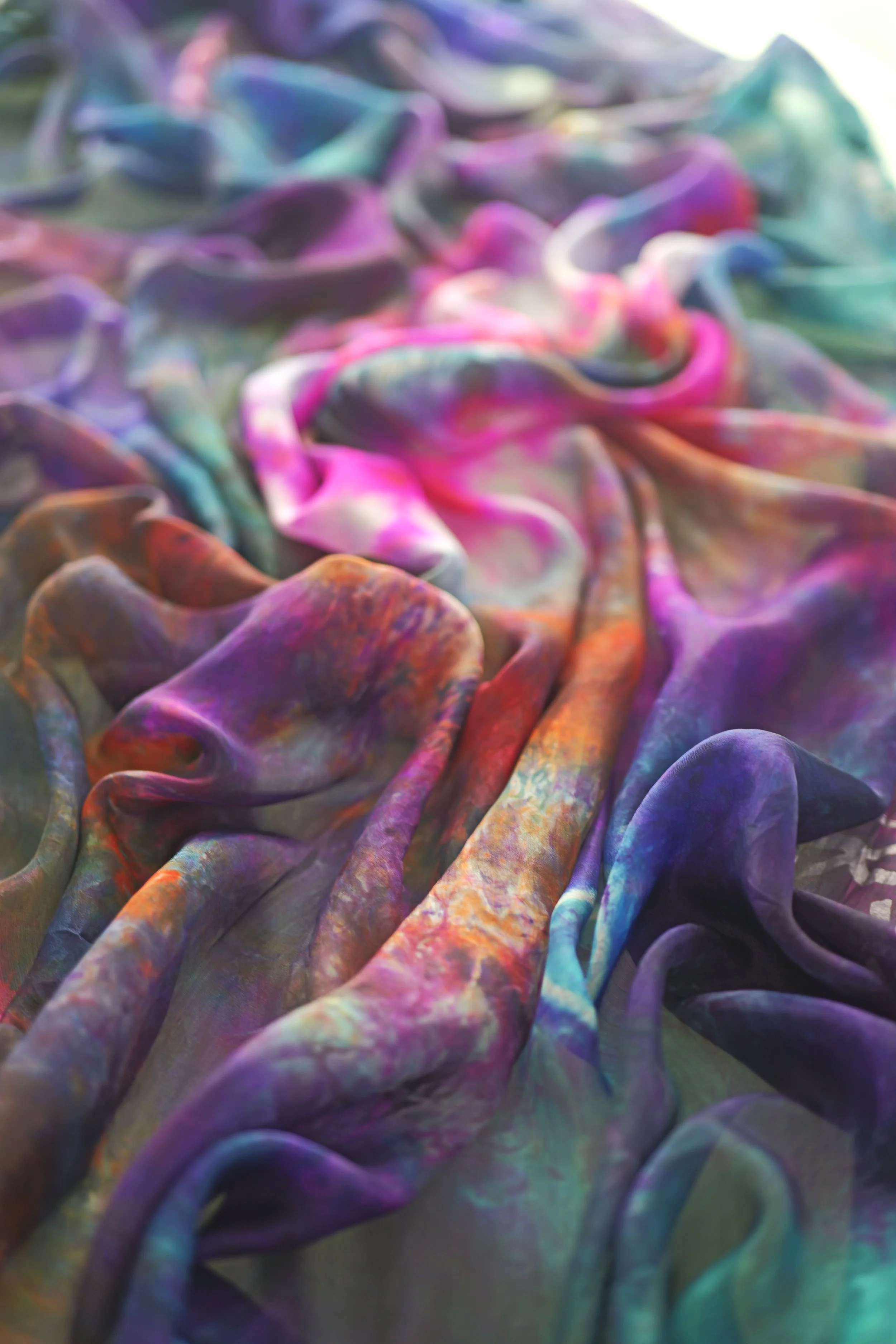 Close-up of colorful, tie-dye silk fabric with swirling patterns and vibrant hues.