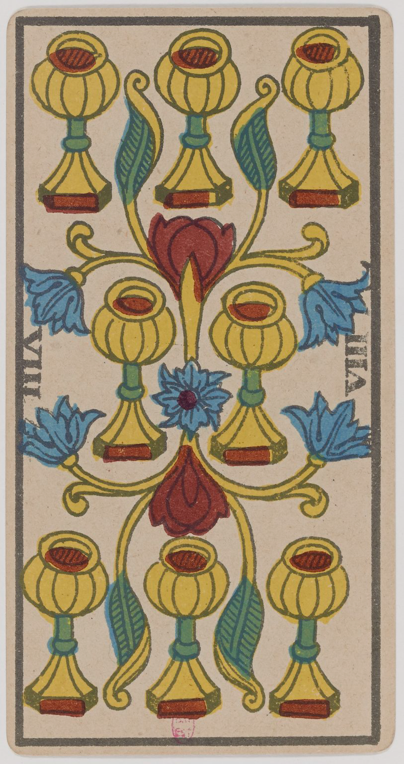 A colorful symmetrical tarot card design with stylized yellow chalices, blue and red decorative elements, and floral motifs on a beige background.