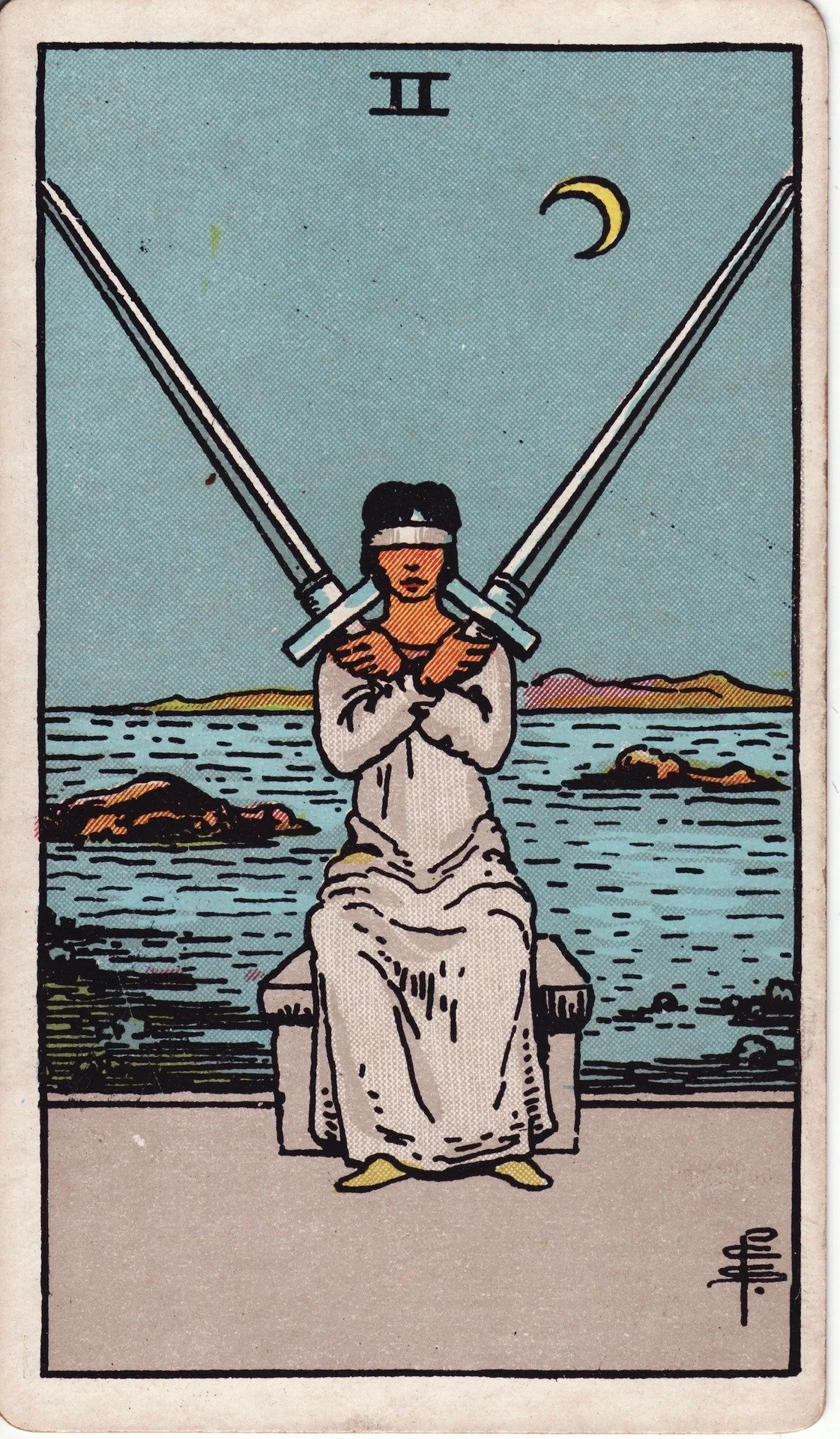 The Two of Swords tarot card depicting a woman sitting on a bench with two crossed swords over her chest, blindfolded, with a body of water and mountains in the background, and a crescent moon in the sky.