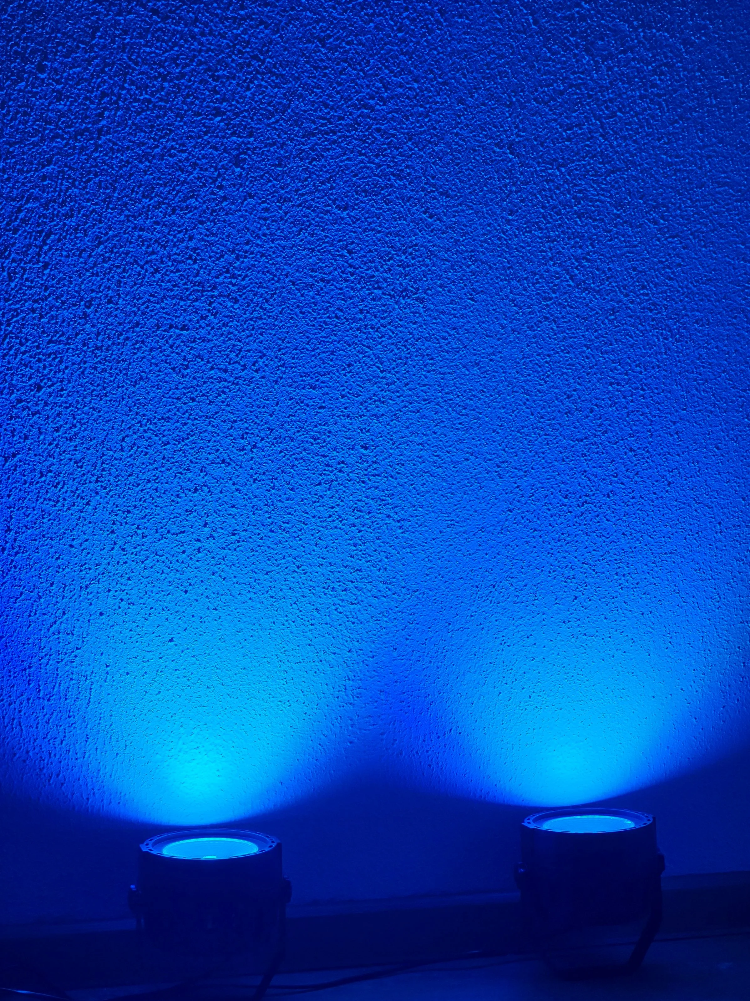Two blue LED lights illuminating a textured wall.