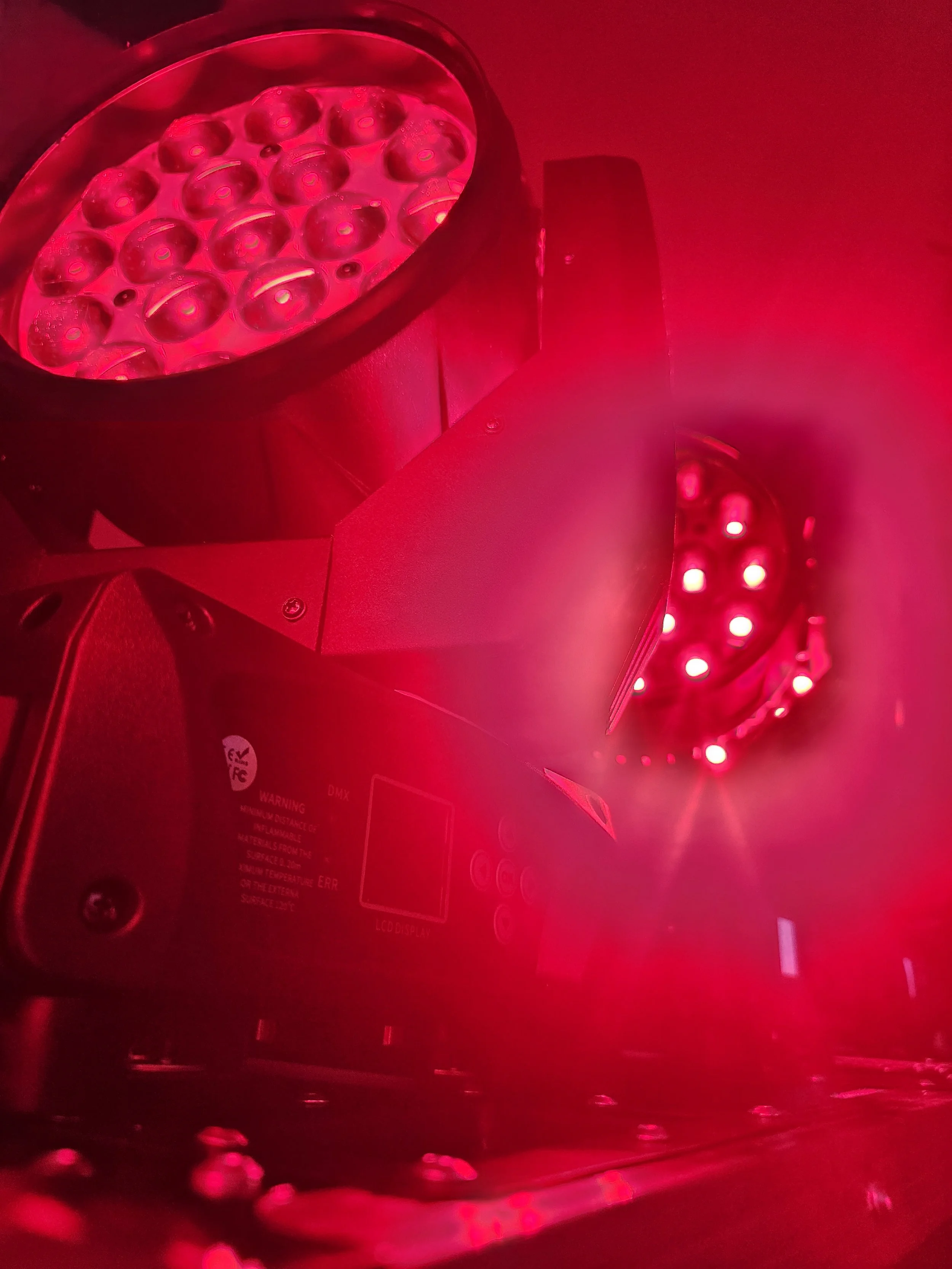 A close-up view of a professional LED grow light emitting red light, mounted on a fixture with multiple small bulbs visible.