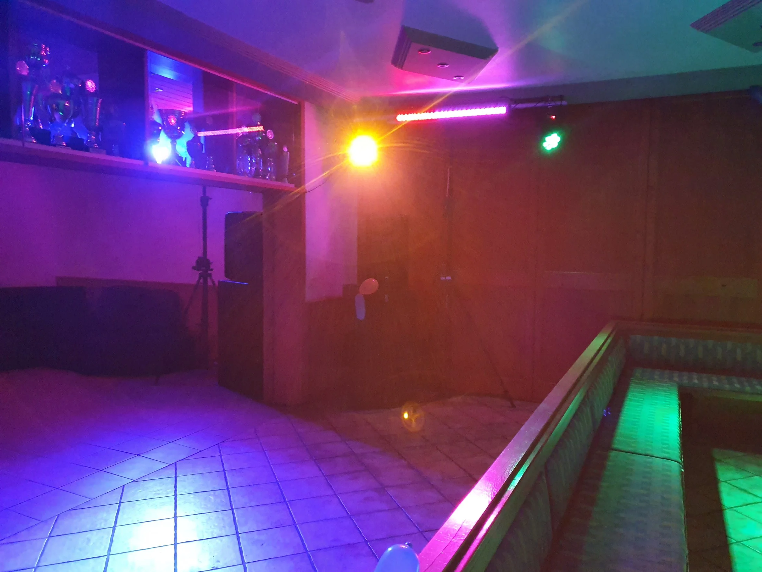 Empty nightclub dance floor with colorful lighting and trophies displayed on a shelf