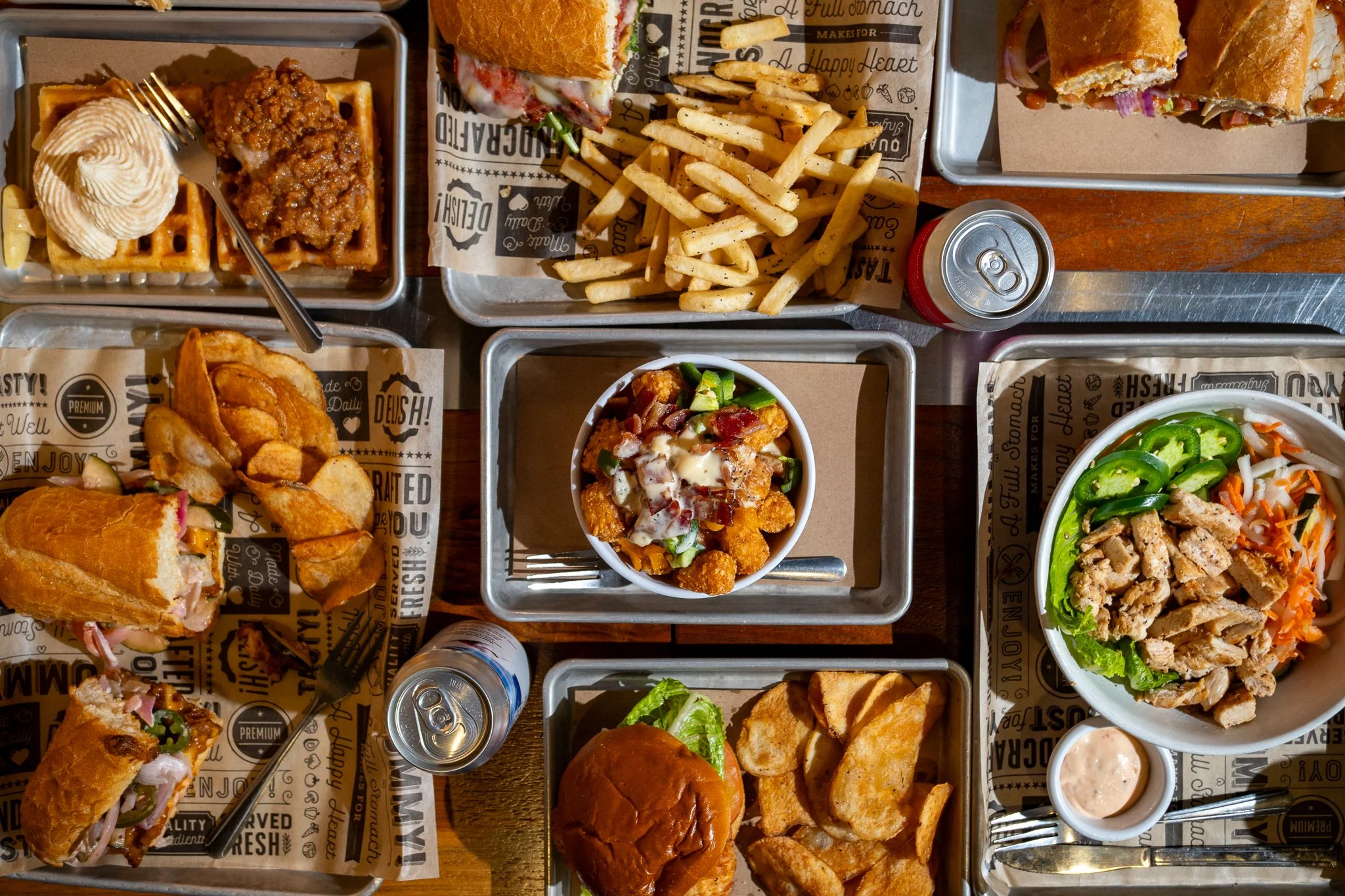 Top-down view of table filled with sandwiches, salads, sides, and other menu items from Zeps EPIQ