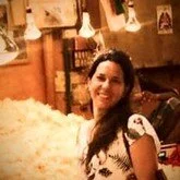 Une femme souriante dans un restaurant, entourée de fleurs blanches