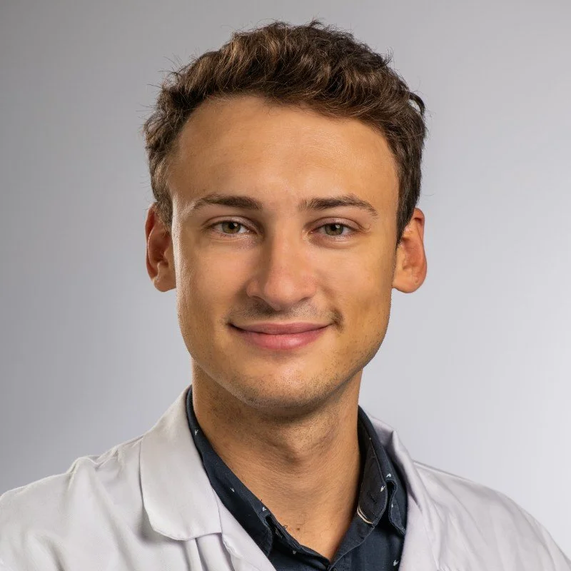 Jeune homme en blouse blanche avec fond neutre.
