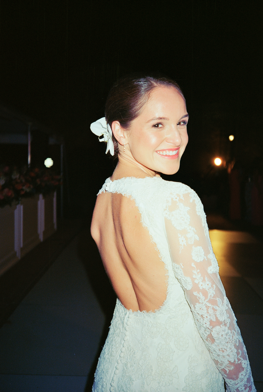 Woman in a white wedding dress smiling on the dance floor at night