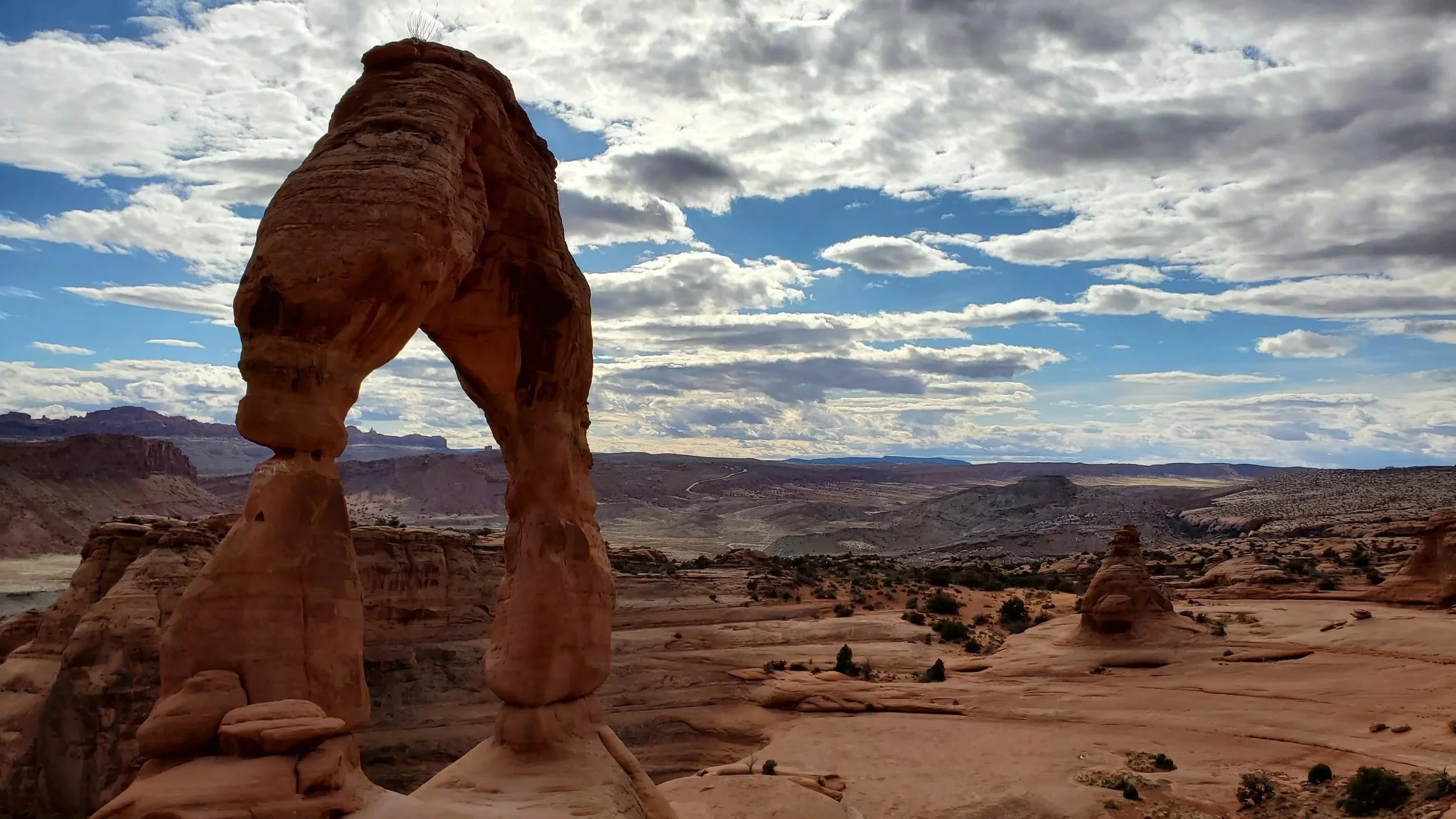 A natural sandstone arch formation in a desert landscape under a partly cloudy sky. Utah, Arches National Park