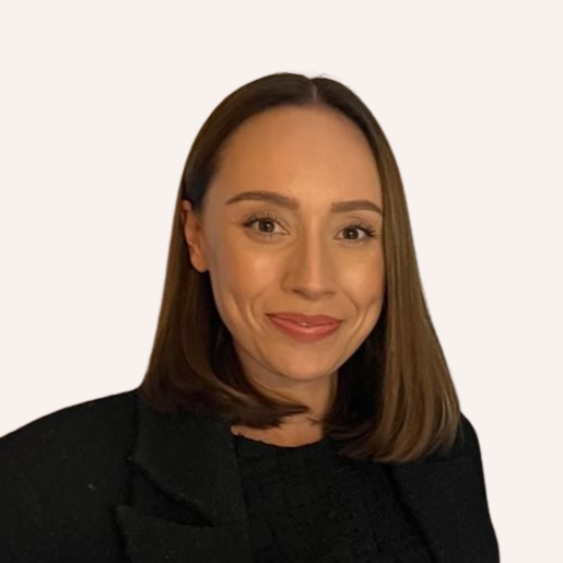A woman with shoulder-length brown hair, smiling, wearing a black blazer and top, with a plain light-colored background.