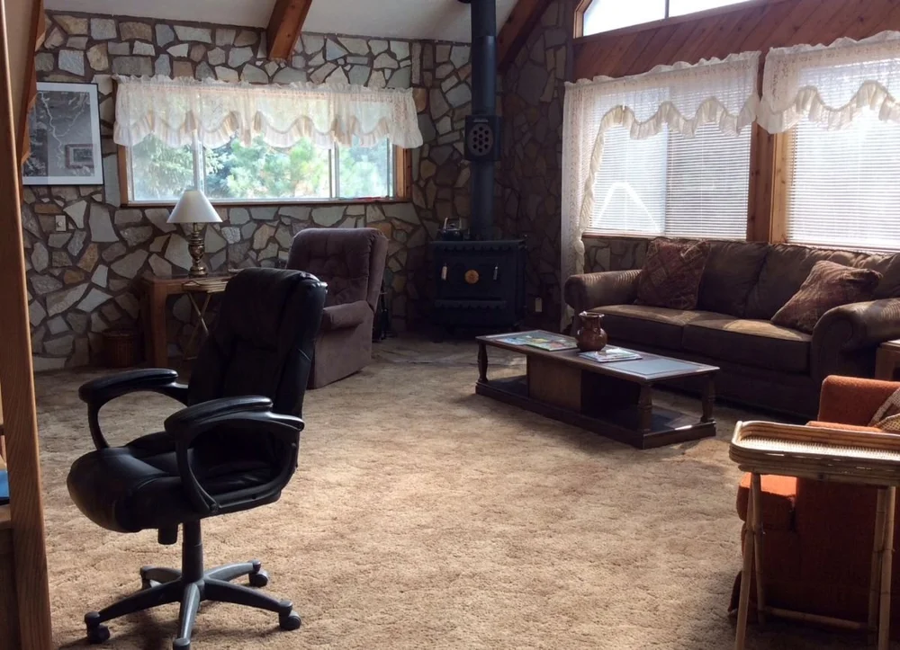A rustic living room with a fireplace and cozy couch in a rental cabin in Elk City, Idaho