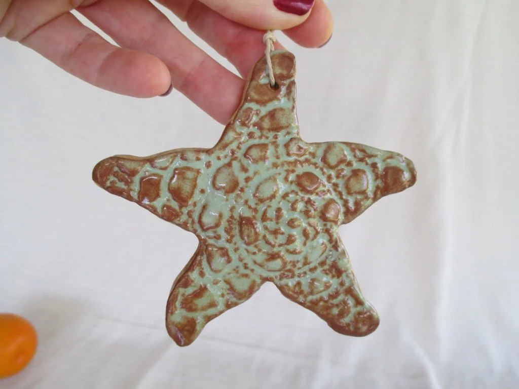 A star-shaped ceramic ornament with a raised, textured pattern being held by a hand.