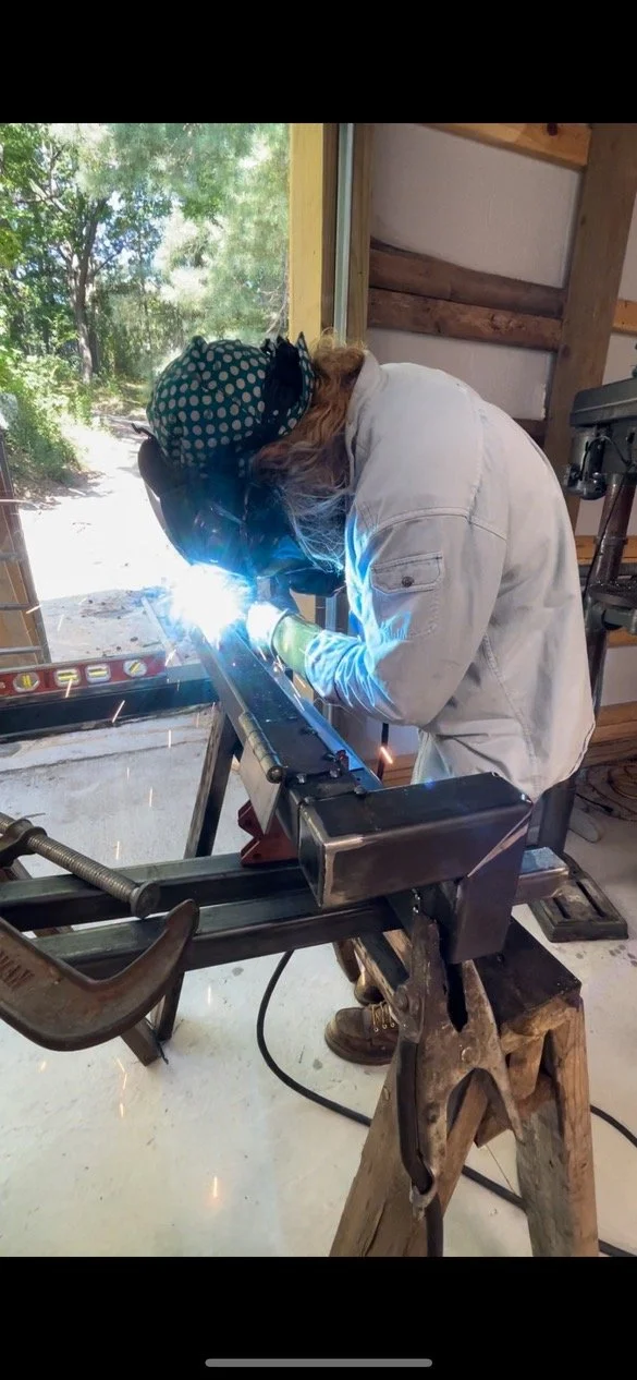 A person welding a custom handrail on a workbench inside a workshop in Traverse City, Michigan.