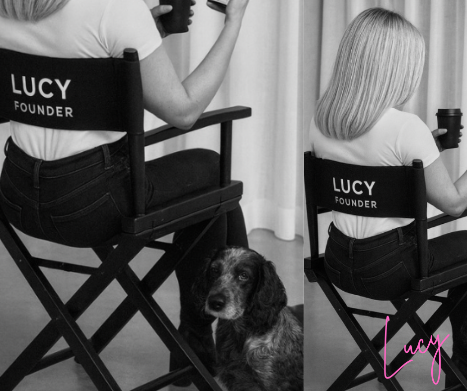 Black and white photo of a woman sitting on a director's chair with "LUCY FOUNDER" printed on the back, holding a coffee cup. A dog is sitting under the chair, looking at the camera. The woman has long blonde hair and is wearing a white shirt and black pants.