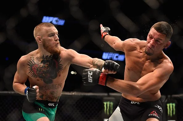 Two male mixed martial artists fighting inside the octagon octagon during a UFC match, one throwing a punch at the other.