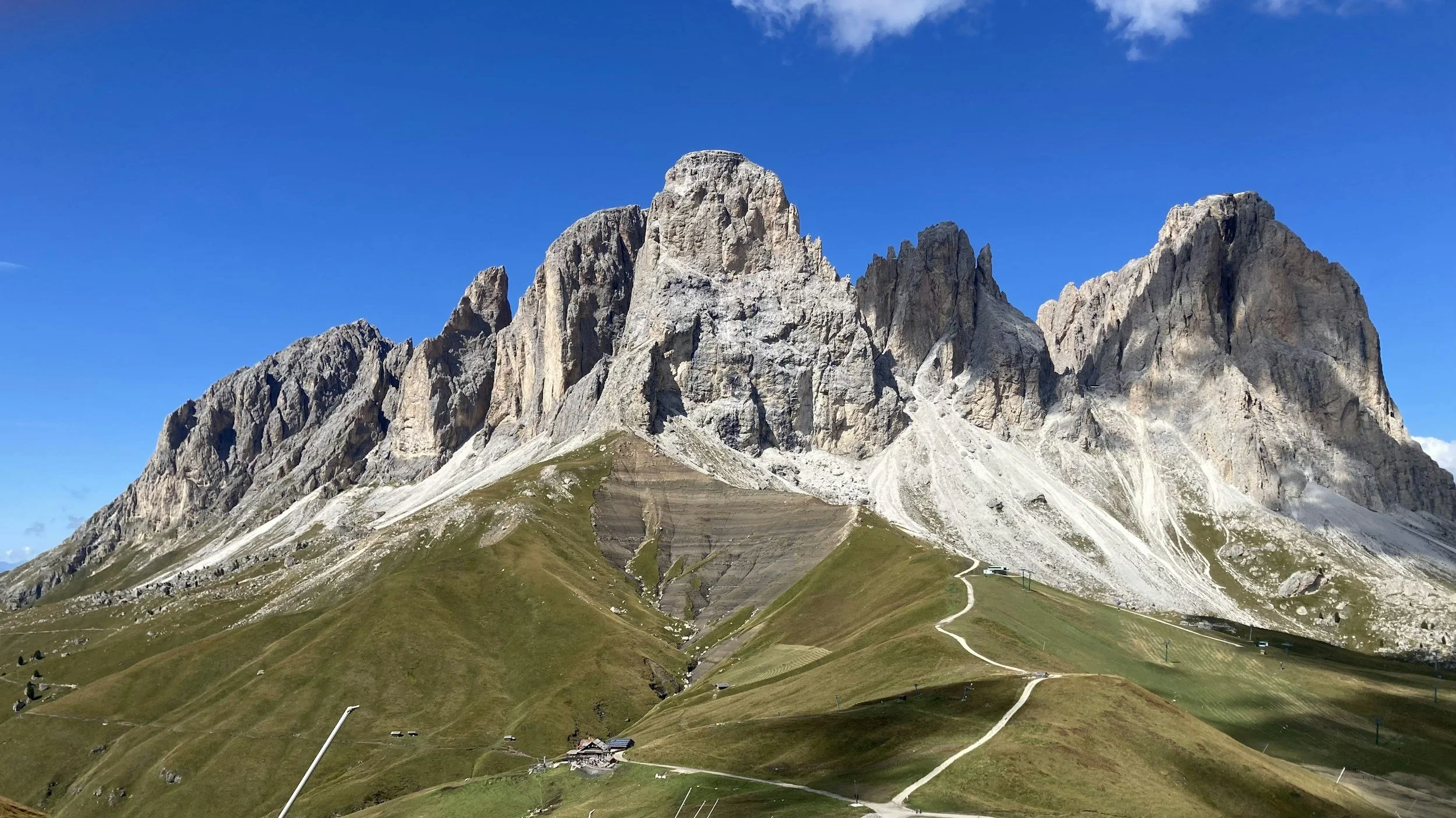 Mountain range with rocky peaks and grassy slopes under a blue sky.