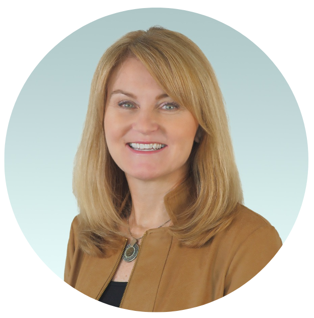 A woman with blonde hair smiling, wearing a brown jacket and a necklace, against a light blue background.