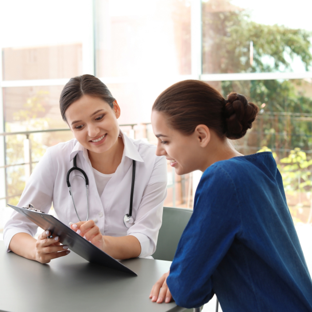 A female doctor showing an X-ray to a female patient in a bright medical office.