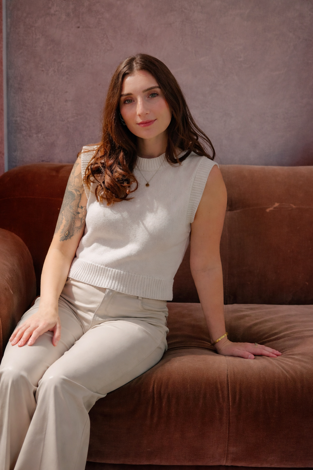 A woman comfortably seated on a couch, legs crossed, exuding a calm and contemplative demeanor.