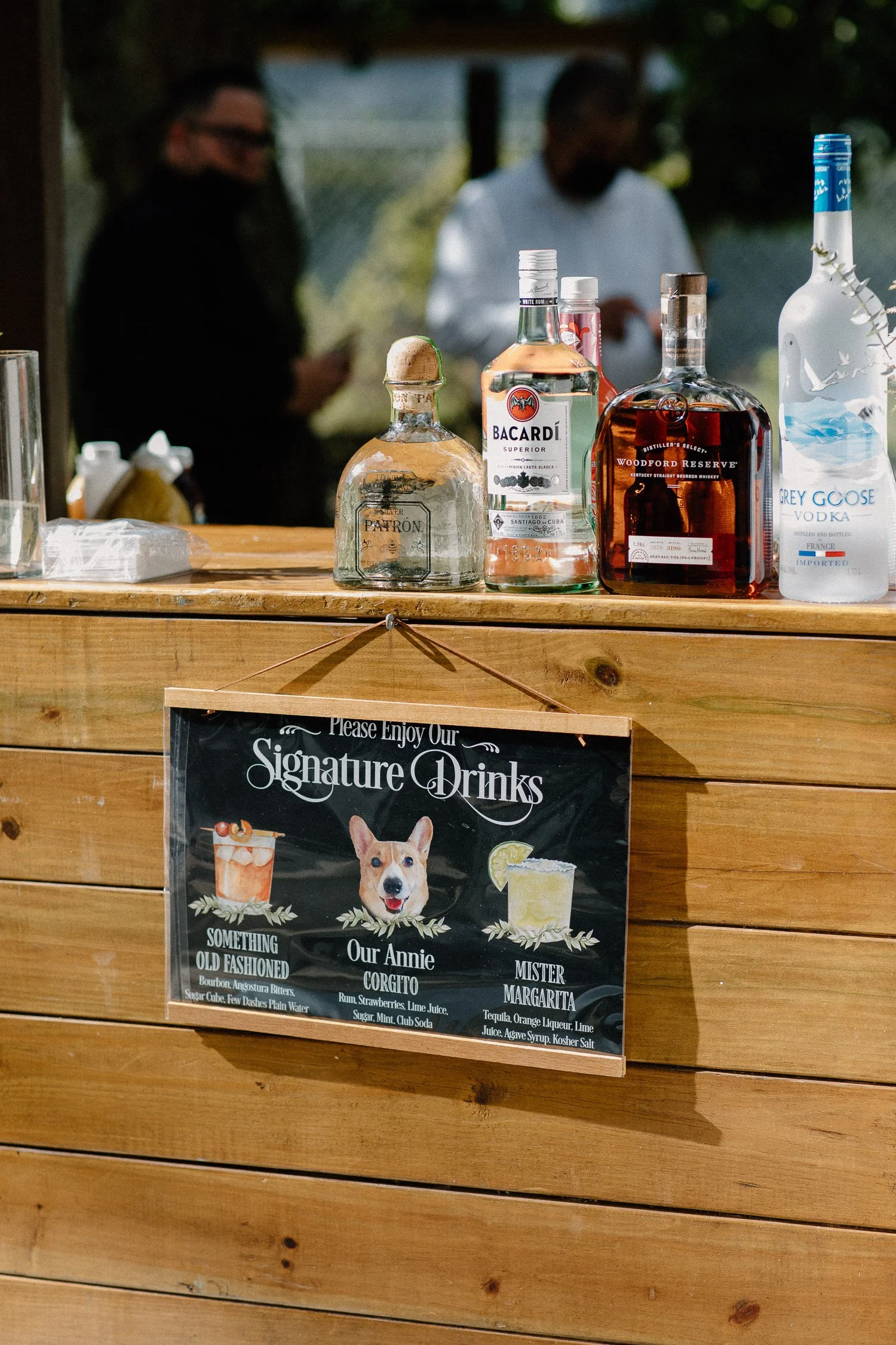 Bar with bottles of liquor and a sign listing signature drinks, including Something Old Fashioned, Our Annie, and Mister Margarita.