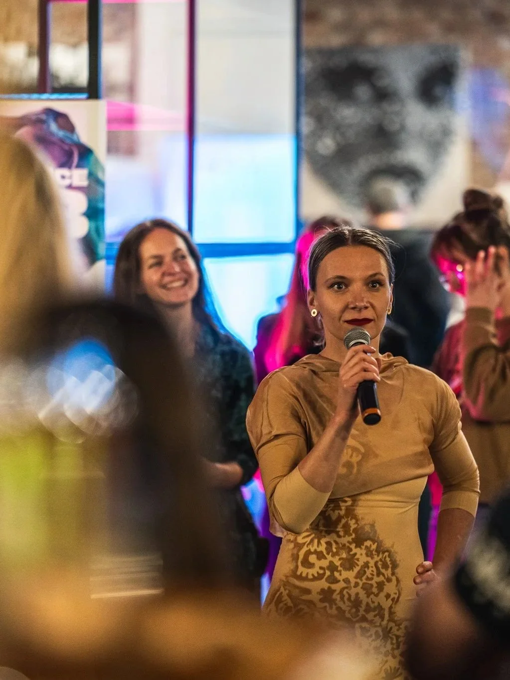 A woman holding a microphone in a crowded room.