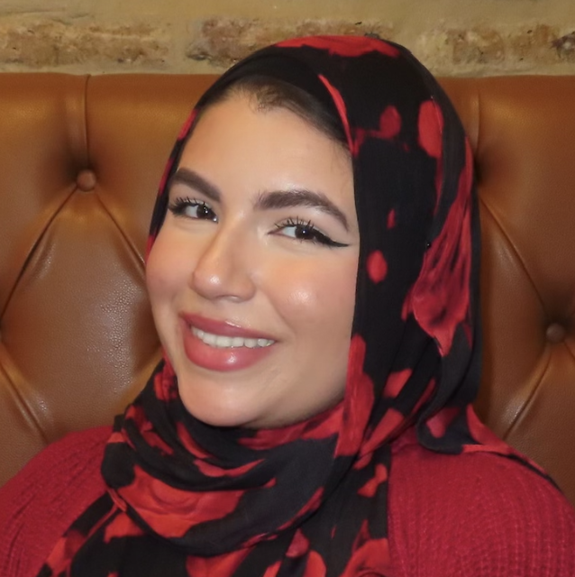 A middle-aged man with light brown hair and blue eyes, smiling. He is wearing a dark blazer over a light blue collared shirt, against a gray background.