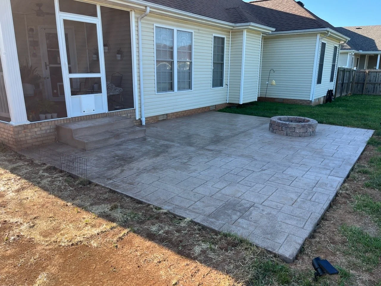 Stamped concrete patio with a built-in fire pit, featuring decorative stone design.