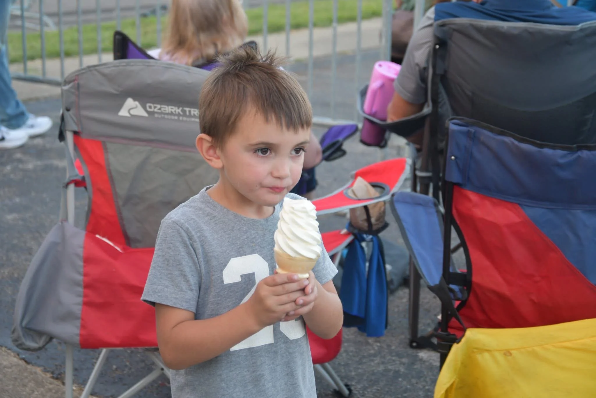 Young boy in a gray t-shirt holding a soft-serve ice cream cone.