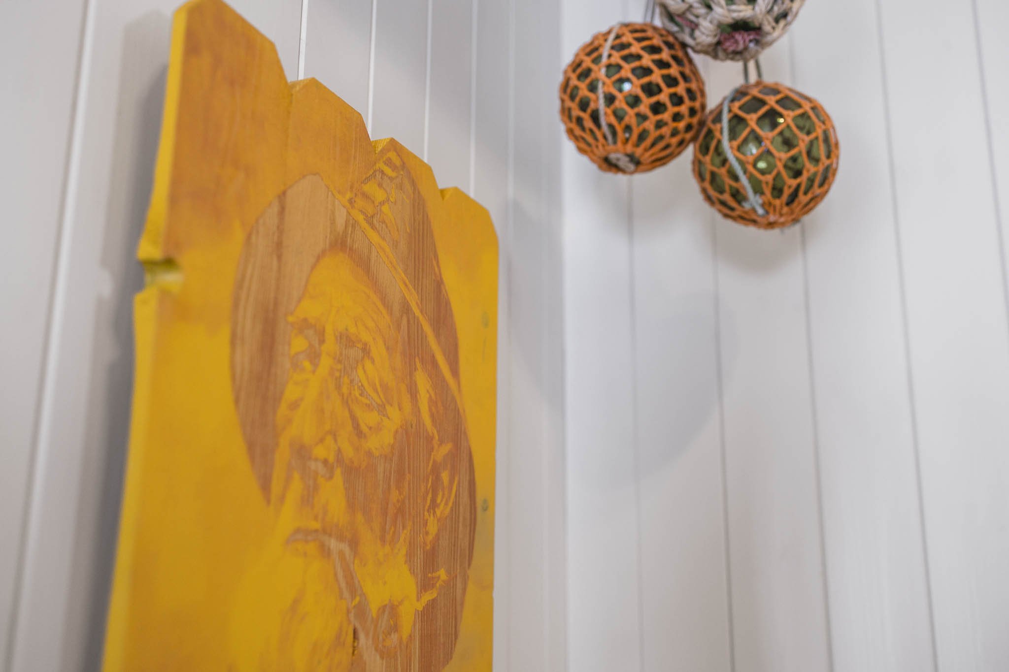 Decorative paper lanterns with orange netting hang from the ceiling, and a colorful artwork with a giraffe silhouette is on the wall behind them near a white-paneled wall.