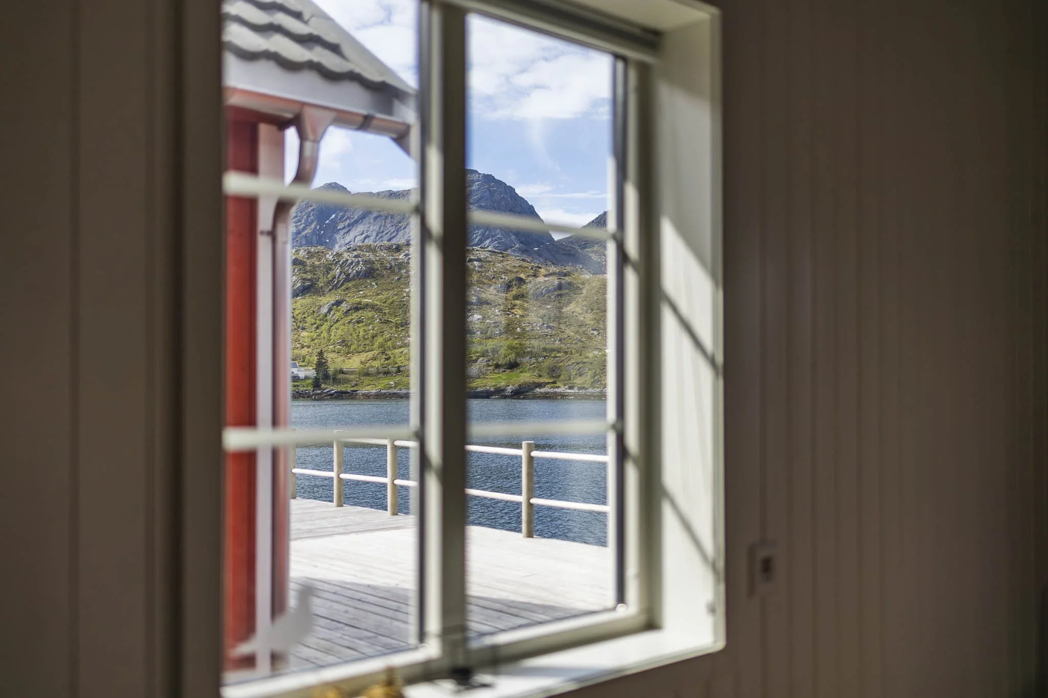 View of mountains and water seen through a window with white shutters.