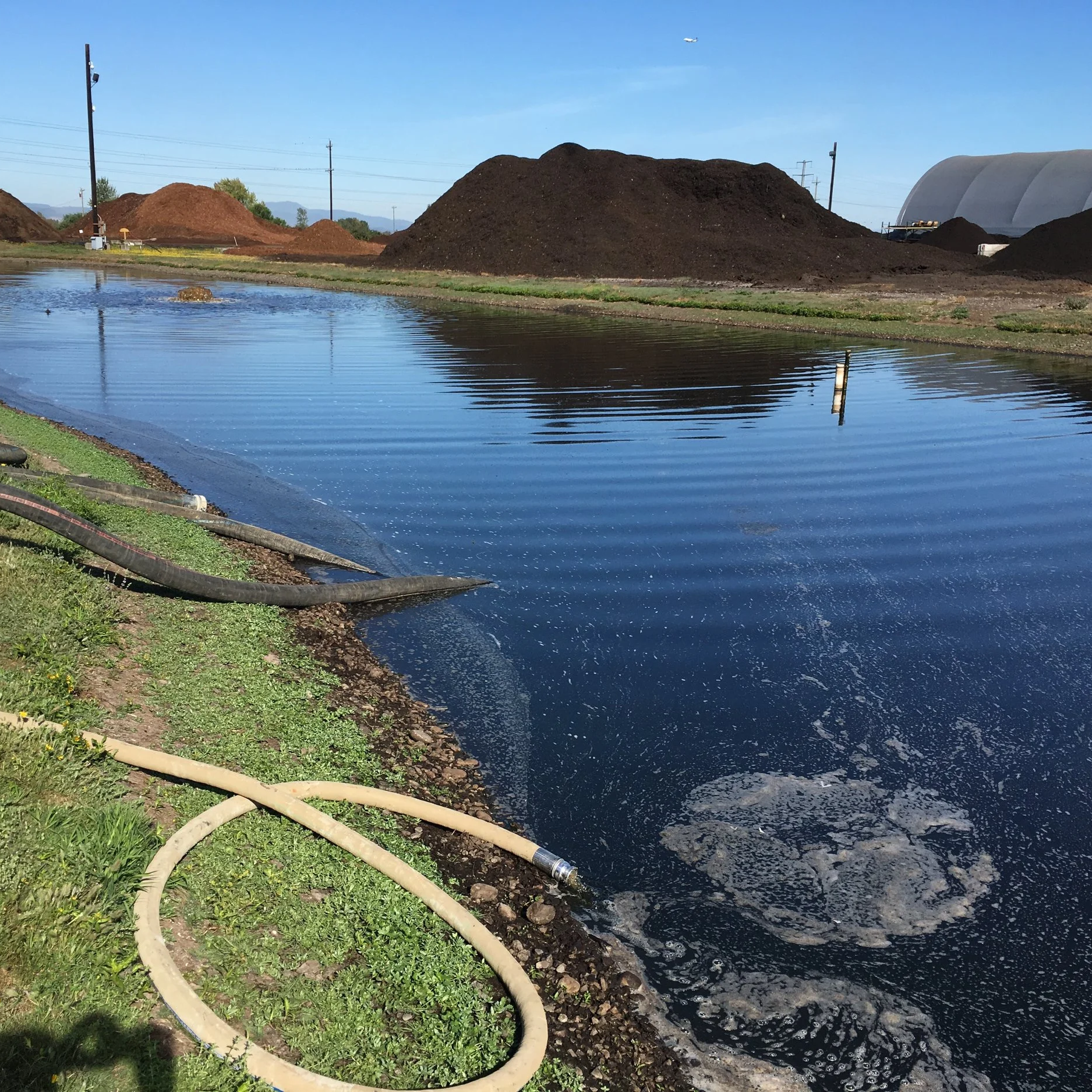 A large pond containing stormwater, compost runoff, and digestate with piles of compost and mulch.  The water is too contaminated with high BOD and high COD.  Will use permanganate to bring the water into compliance for discharge.