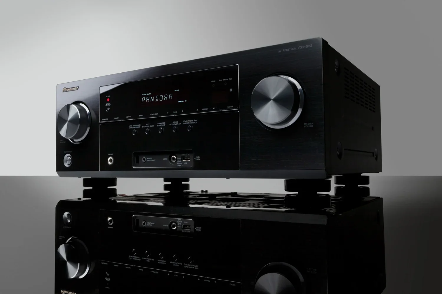 Black audio receiver on a reflective surface with controls and a digital display showing 'Pandora'