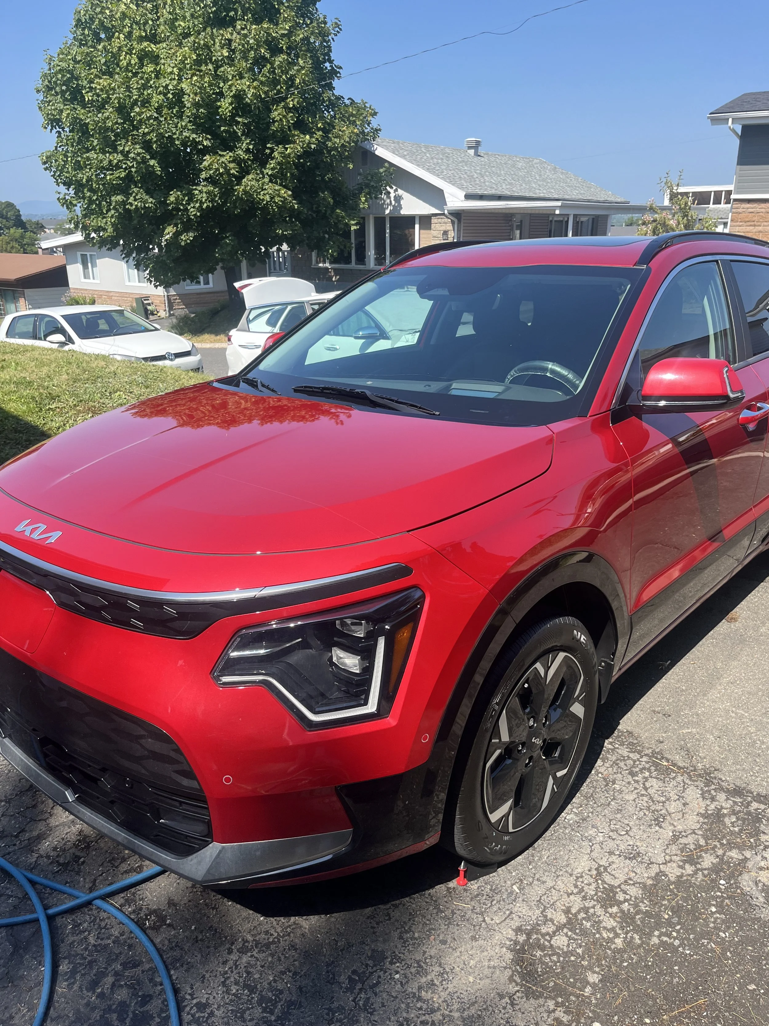Voiture rouge électrique en train d'être lavée dans une allée résidentielle