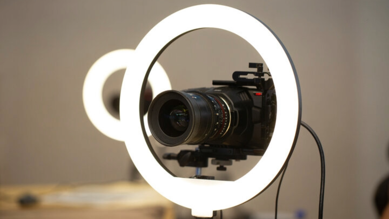 A professional camera mounted inside a white LED ring light, used for photography or videography.