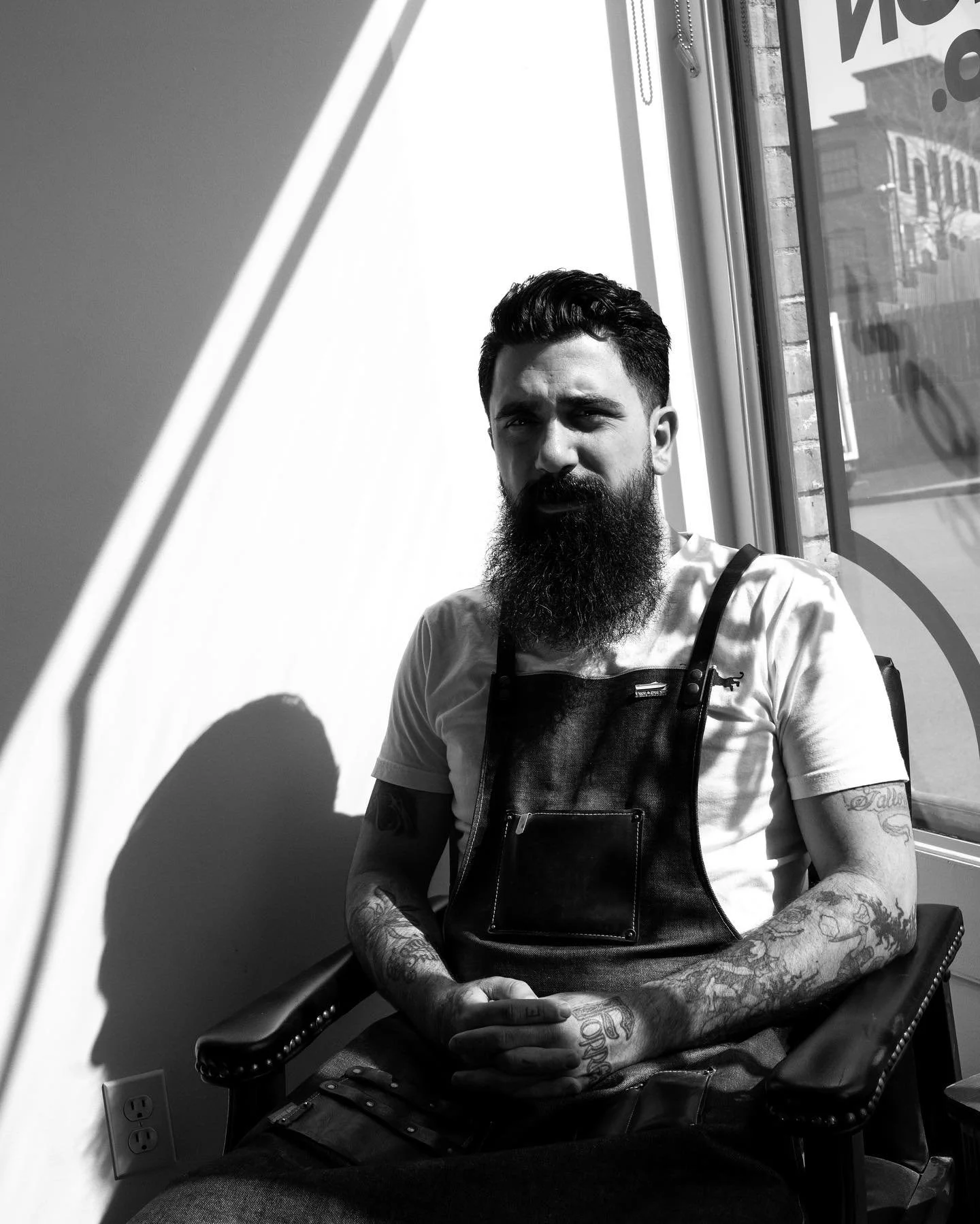 Black and white photo of owner Ian Napoli sitting in the shop while the sunlight streams through the window on him