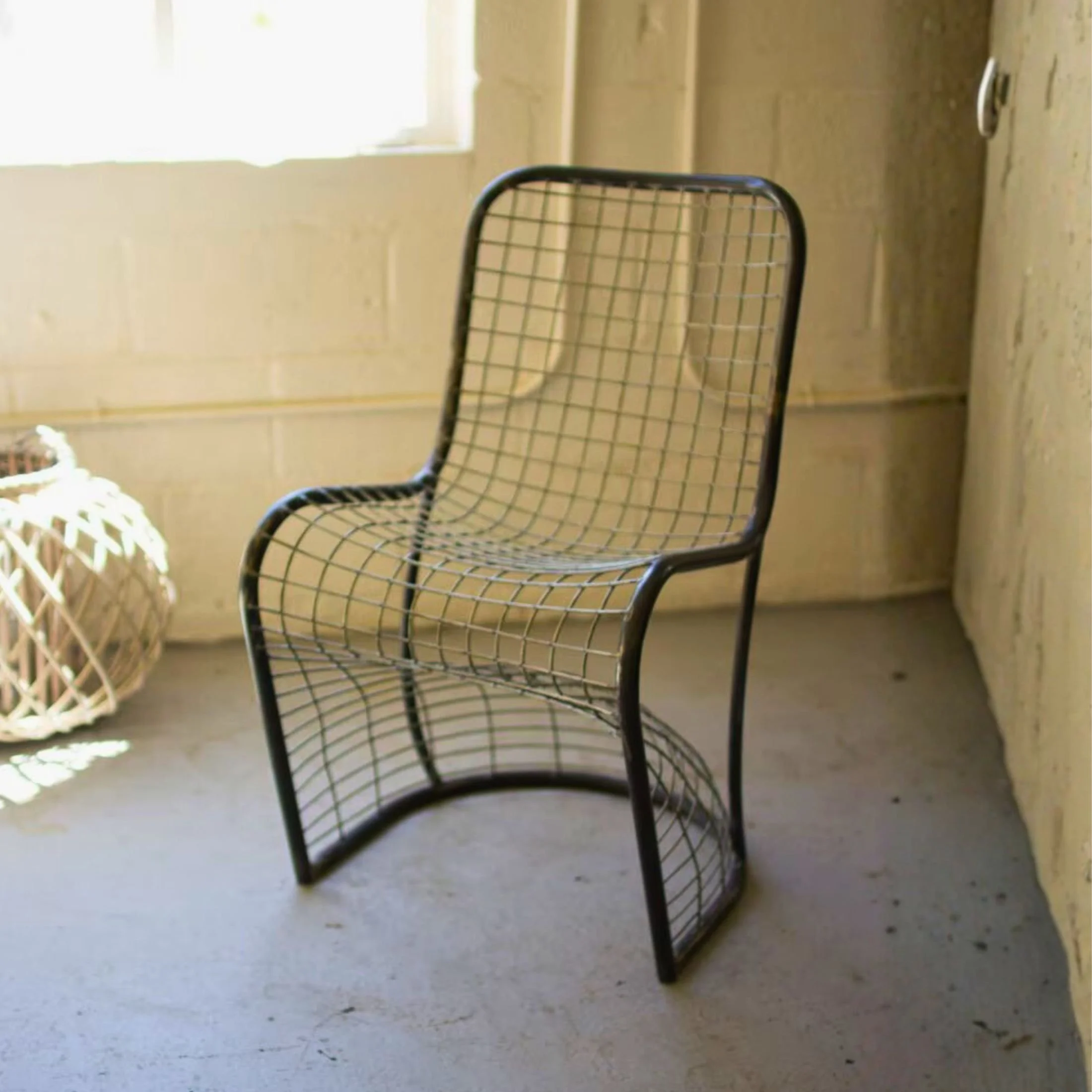 Woven metal S-chair with bent steel frame and sculptural industrial design