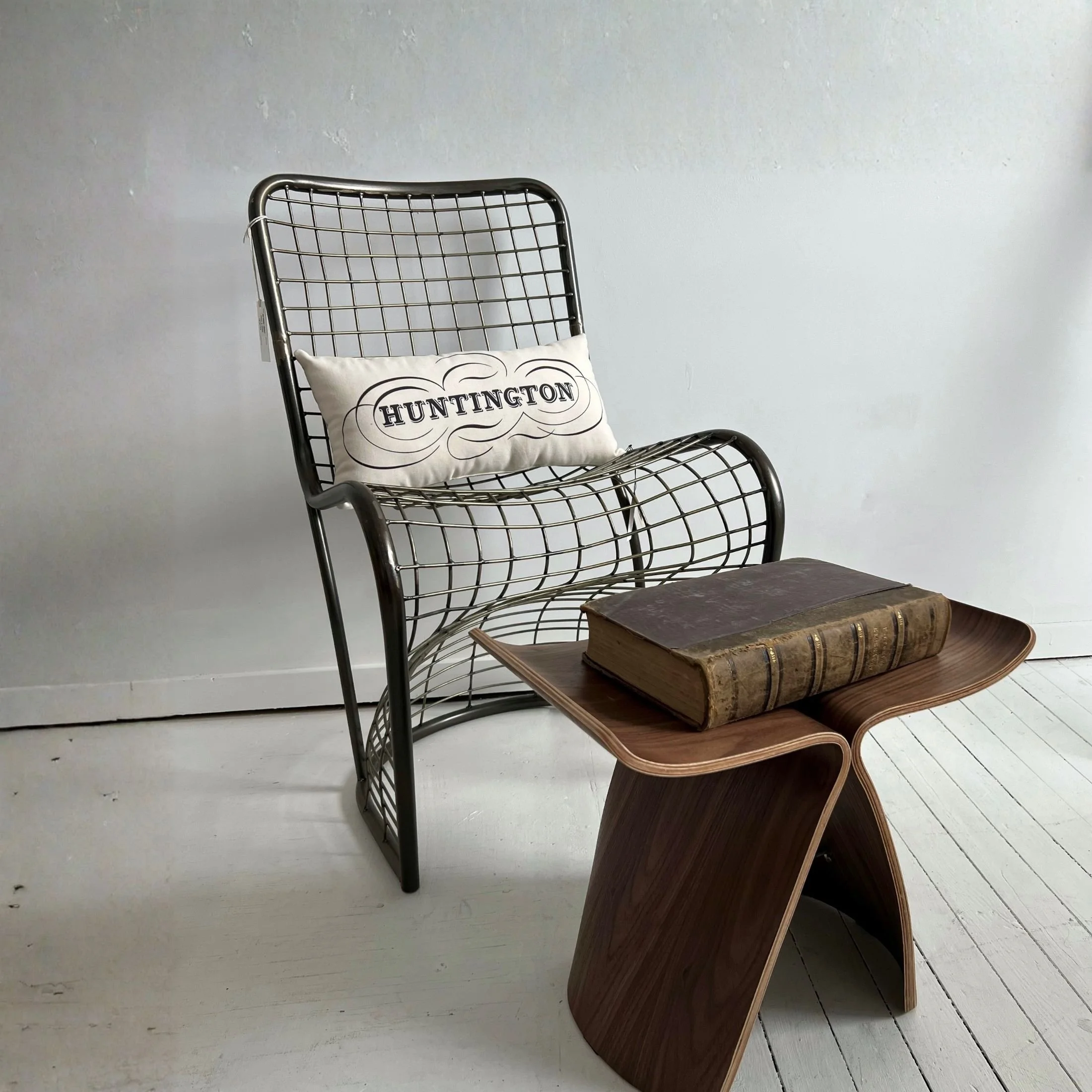 Metal S-chair with woven bent steel frame and sculptural industrial design