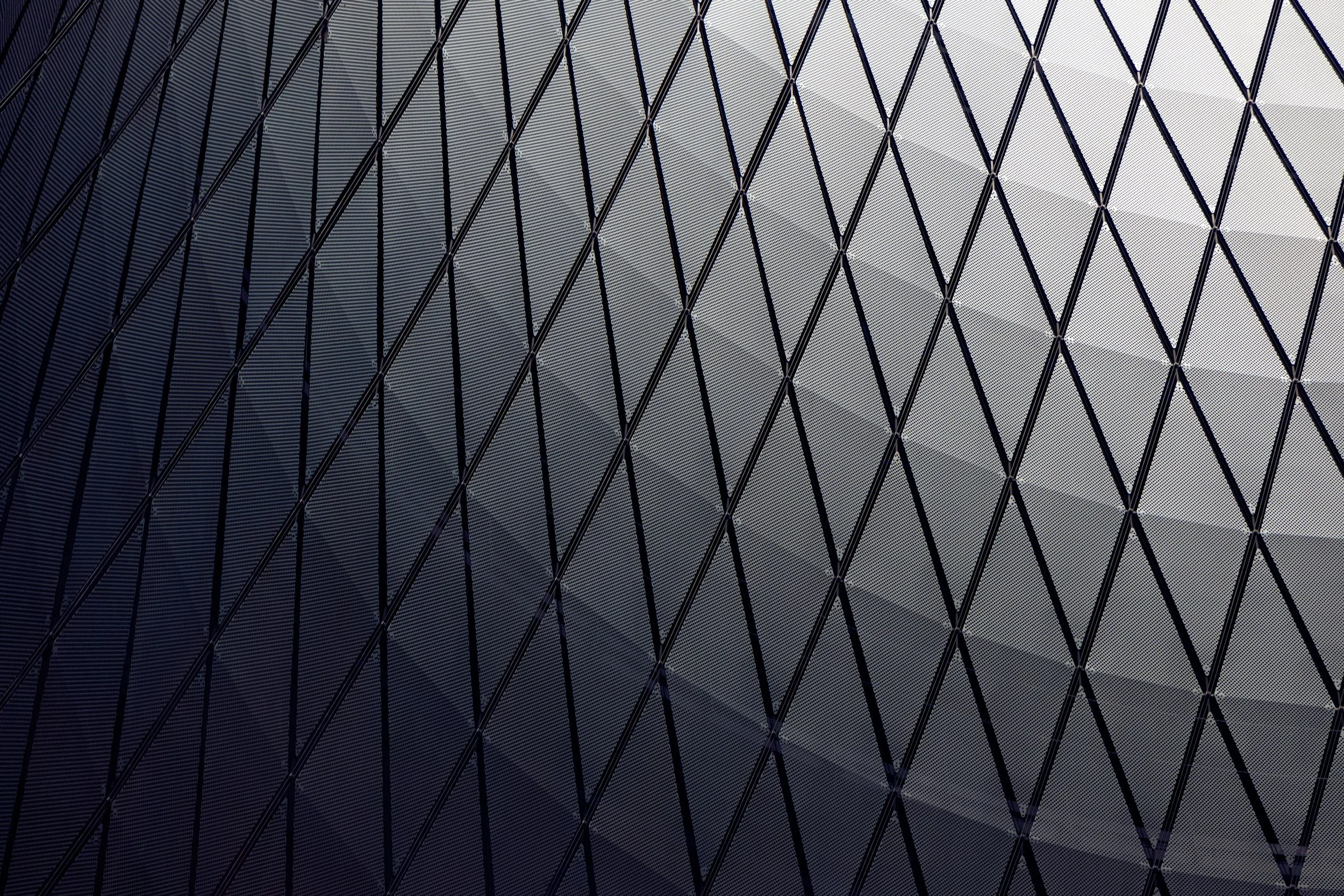 Close-up of a building facade with a metal diamond pattern grid and glass panels reflecting light.