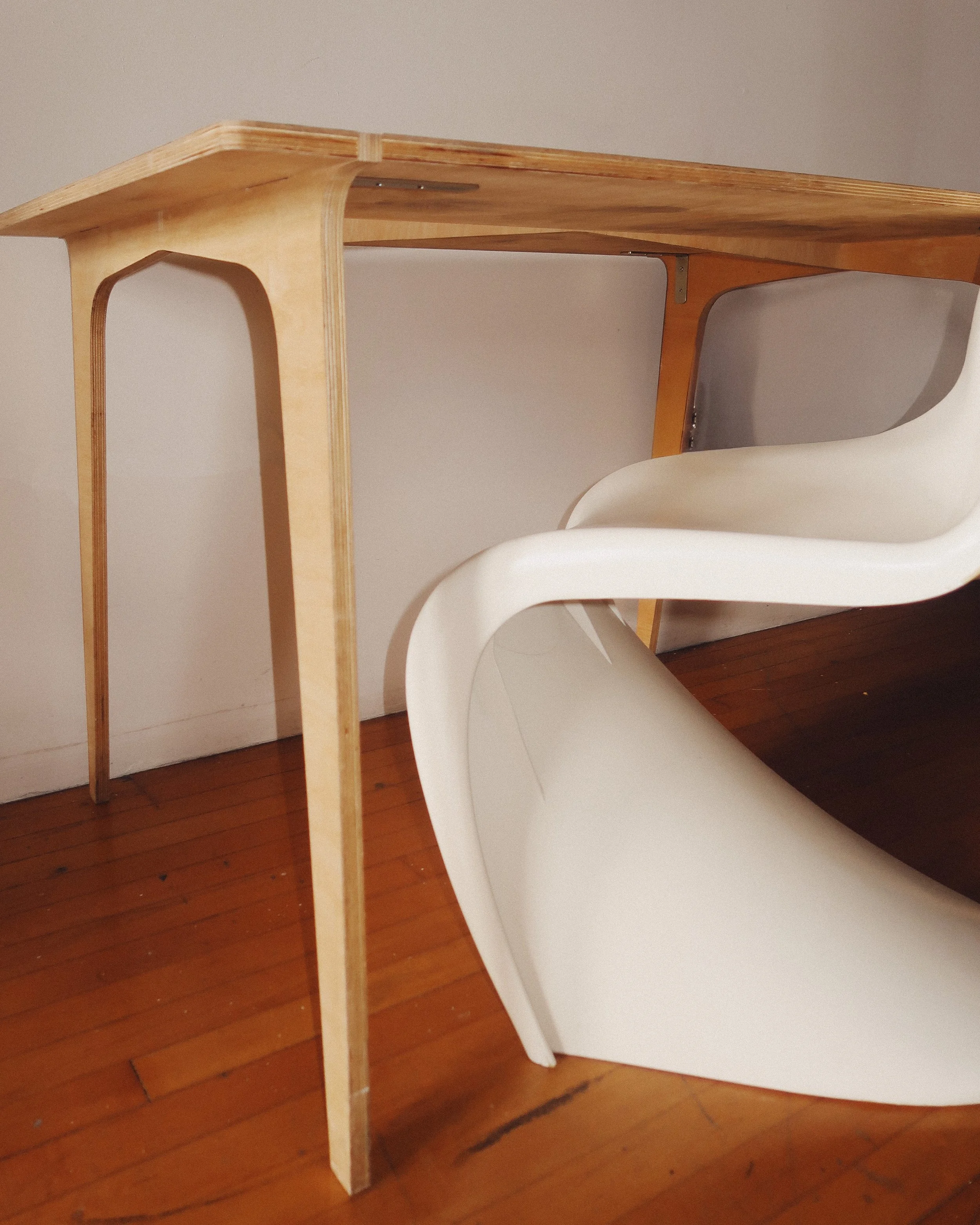 Mid-century modern plywood dining table with bent-leg construction, silver brackets for stability, and a lived-in patina.
