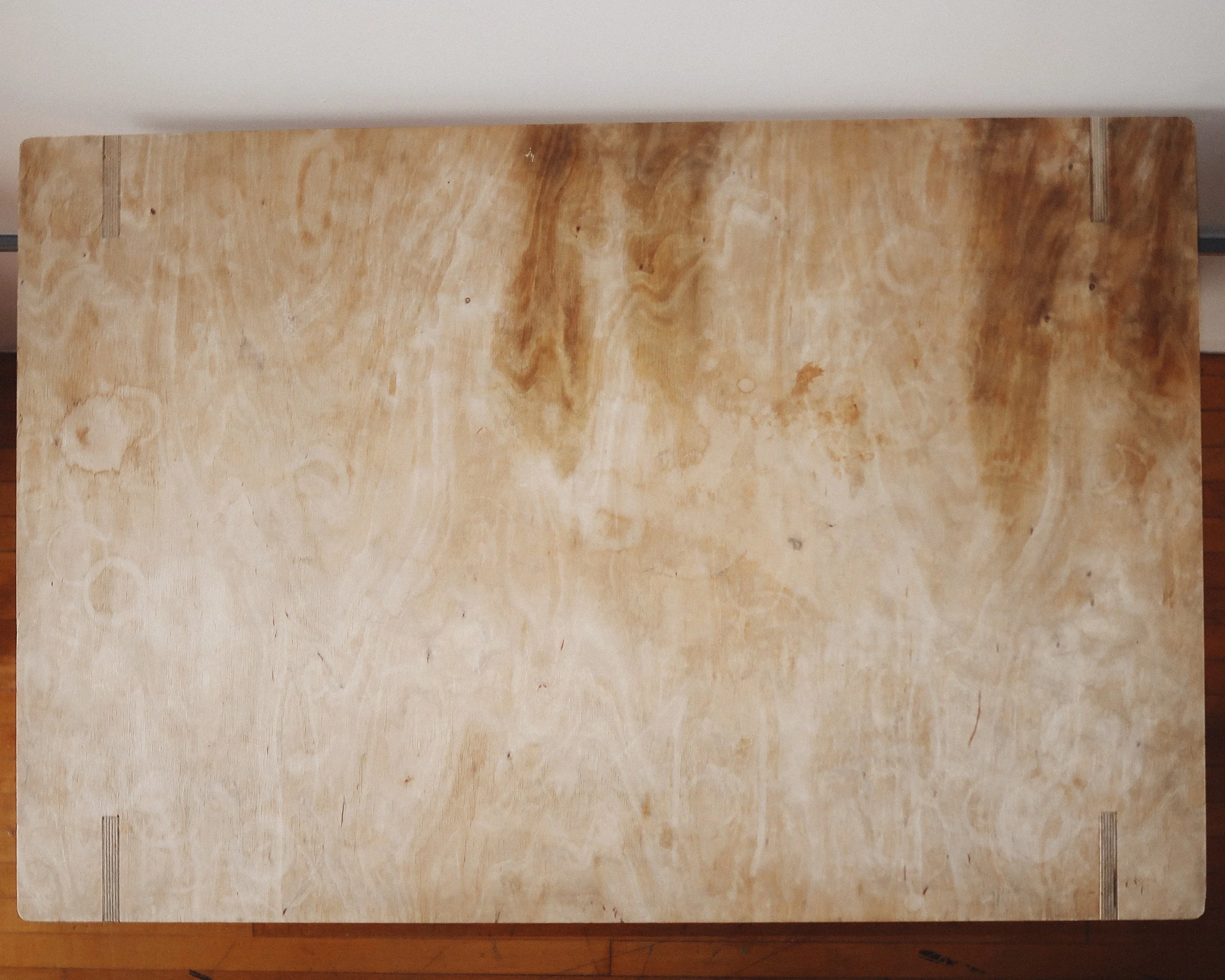 Mid-century modern plywood dining table with bent-leg construction, silver brackets for stability, and a lived-in patina.
