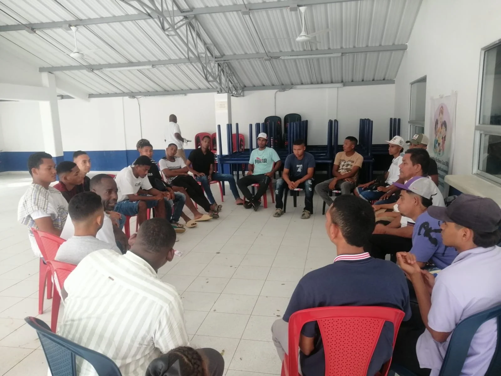 A group of people seated in a circle in a room, participating in a discussion or meeting.