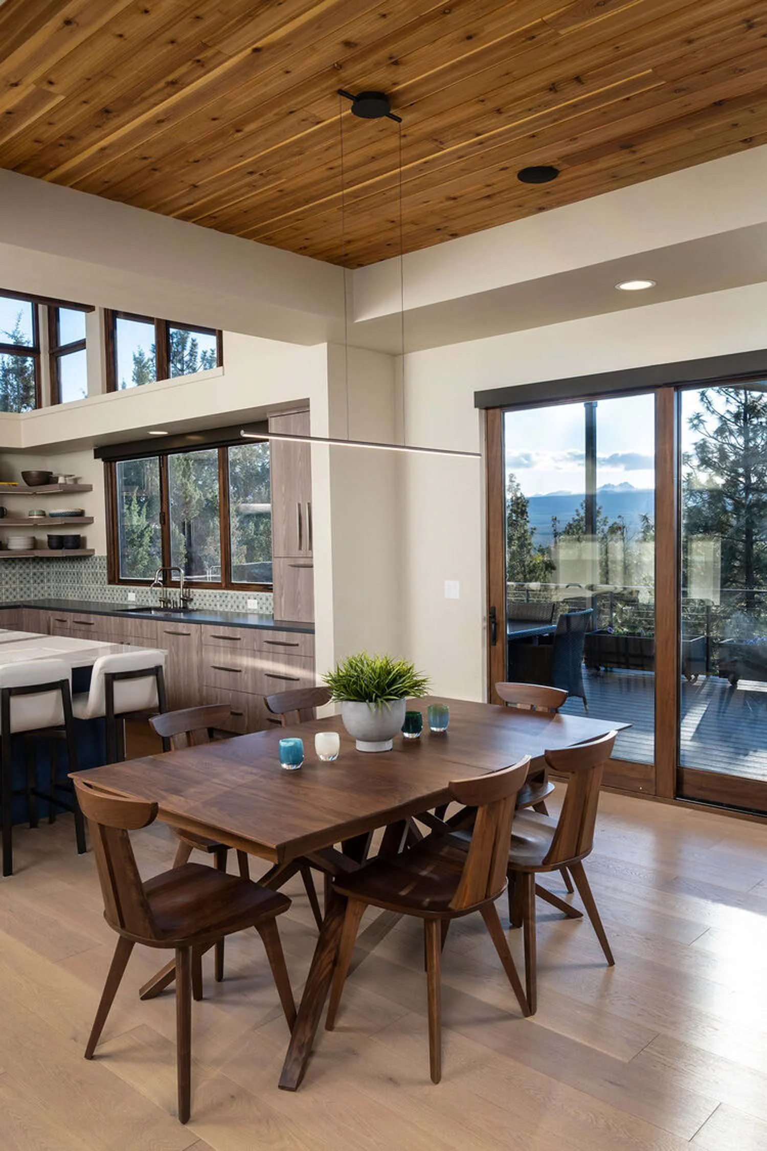 This elegant, modern dining room is a beautiful showcase of masterful interior design by Kristy Yozamp. Featuring a stylish wooden dining table and six comfortable chairs, all accented by a natural plant centerpiece, this space is an example of the s