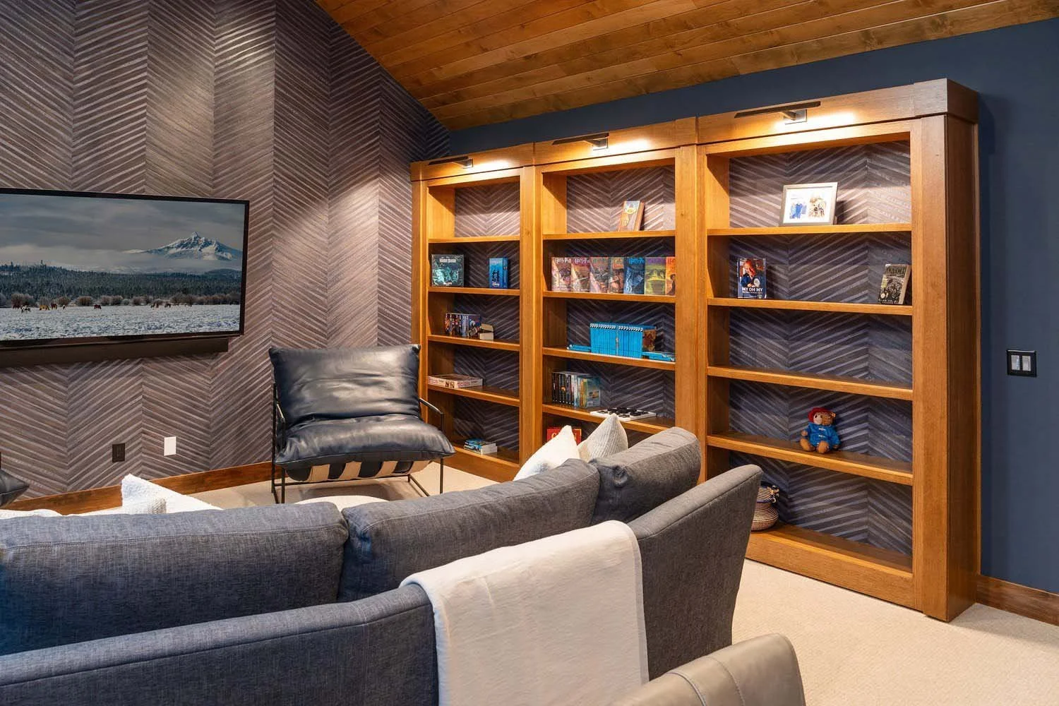 As masterful builders of luxury custom homes in Central Oregon, Pacwest Builders crafted this playful and functional space within the Black Butte Ranch - Bishops Cap home. This modern living room features a comfortable grey couch, a sleek black leath