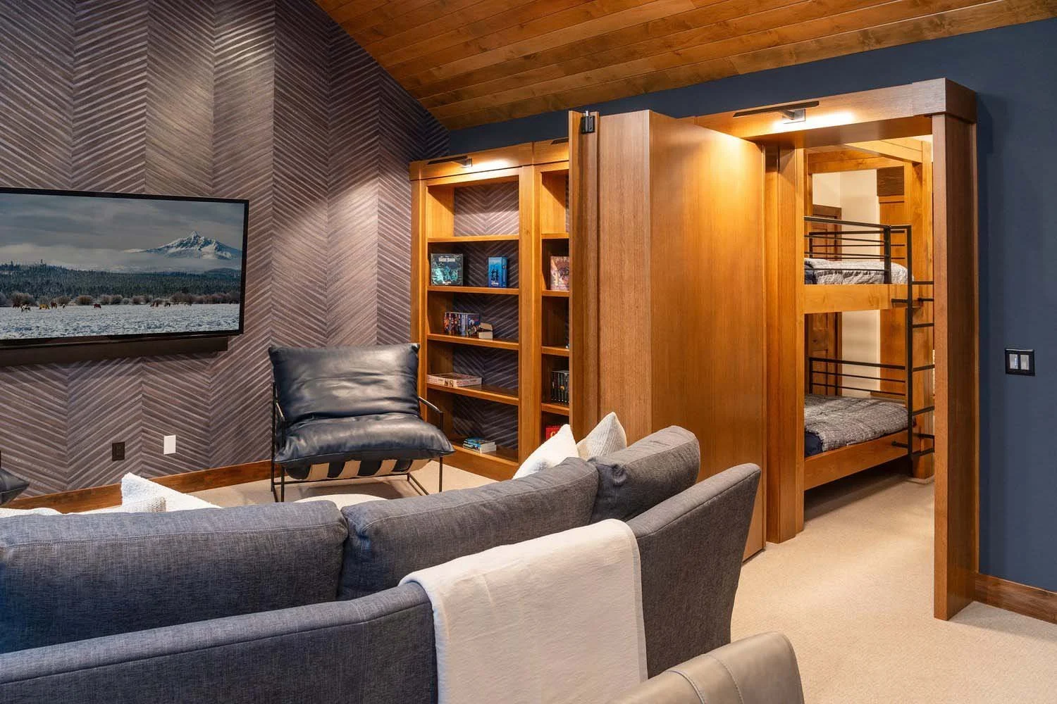 This clever living space at Black Butte Ranch - Bishops Cap in Central Oregon, designed by Pacwest Builders, offers both comfort for adults and adventure for the little ones! Featuring a stylish grey couch, a sophisticated black leather armchair, a f